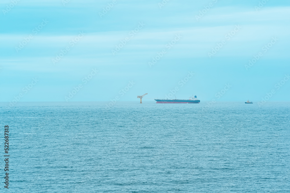 foggy seascape with a tanker near an oil terminal located far out to sea, top view