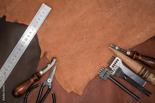 Tools for leather crafting and pieces of brown leather. Manufacture of leather goods. Flat lay top view