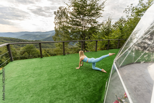 a woman is doing exercises on the terrace of a transparent bubble dome photo