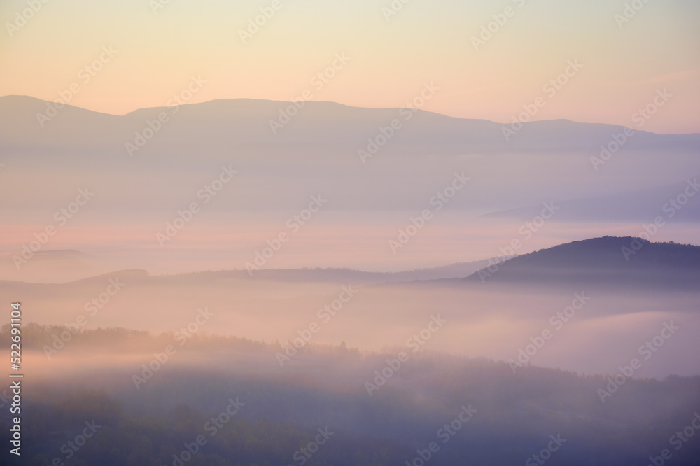 carpathian mountains at foggy sunrise. beautiful autumn landscape with forested rolling hills and glowing cloud inversion in the distance valley