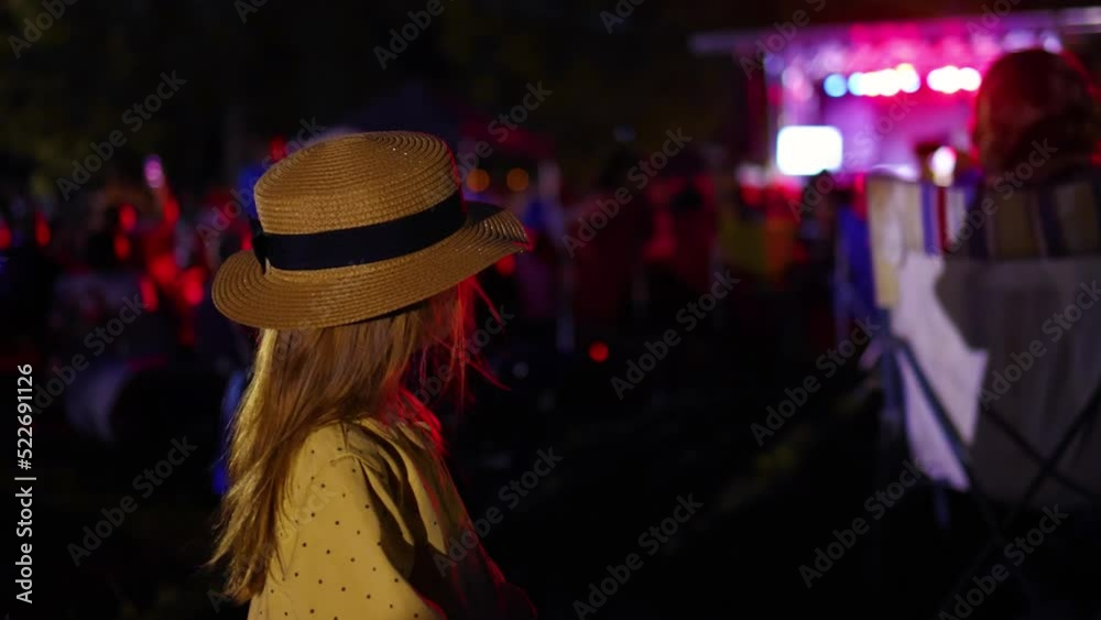 cute little girl enjoys musical show, event on a crowded field at summer night. cute little girl enjoys musical show, event on a crowded field at summer night.
