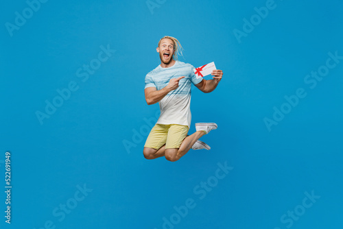 Full size young blond man with dreadlocks 20s he wear white t-shirt jump high point index finger on gift certificate coupon voucher card for store isolated on plain pastel light blue background studio