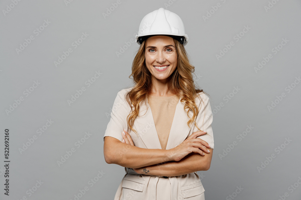 Young confident happy architect engineer designer employee white woman 30s she wear pastel clothes hardhat isolated on plain light grey background studio portrait. People work on architecture project. Young confident happy architect engineer designer employee white woman 30s she wear pastel clothes hardhat isolated on plain light grey background studio portrait. People work on architecture project.