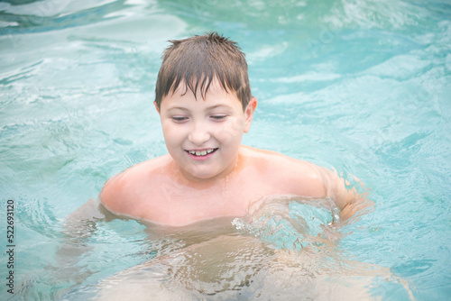 A little smart boy is swimming in swimming pool. Horizontal view. Summer. © Di_Ilikaeva