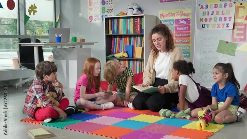 Female teacher reading story to group of elementary pupils in school classroom