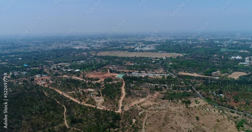 Aerial shot of flat dry landscape with trees, city with palaces in background