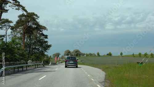 Black metallic car SUV driving on country road street driver slowly following exploring combi ev electric hybrid gas fuelled happy family vacation speeding empty street safety sunny travler photo