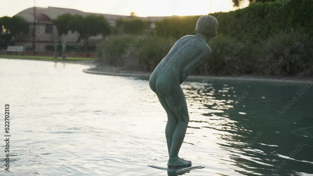 Statue of a naked woman standing on a water fountain at sunset 