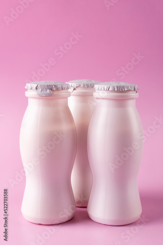 Bottles of milk yogurt (kefir) on a pink background. Space for text. Vertical photo. The concept of probiotics (bifidobacteria) and healthy nutrition. Packaging of fermented milk products.