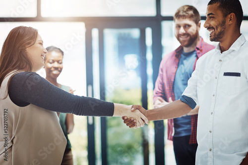 Business people giving handshake, welcoming new employee and standing united while colleagues clap in meeting at work. Coworkers shaking hands, celebrating success or congratulating on a promotion