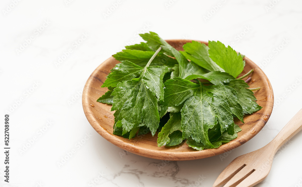 heap of white mugwort or wormwood Artemisia lactiflora in wooden plate on white table background. superfood white mugwort leave background heap of white mugwort or wormwood Artemisia lactiflora in wooden plate on white table background. superfood white mugwort leave background