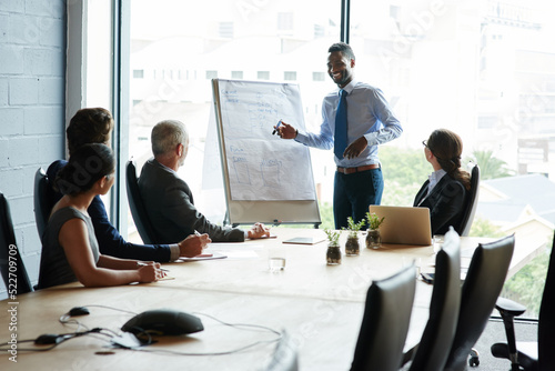 Young black man doing leadership presentation on innovation at business shareholder meeting in office. Diverse work colleague group talking about company mission and vision development strategy. photo