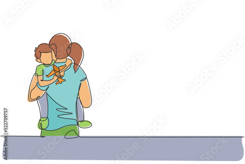 One continuous line drawing of young mother hugging her sleepy son while holding airplane toy at home, family life. Happy parenting concept. Dynamic single line draw design vector graphic illustration
