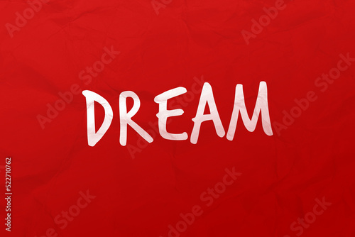 Testo Dream, scritto su carta stropicciata stile post it di colore rosso. Messaggio positivo.