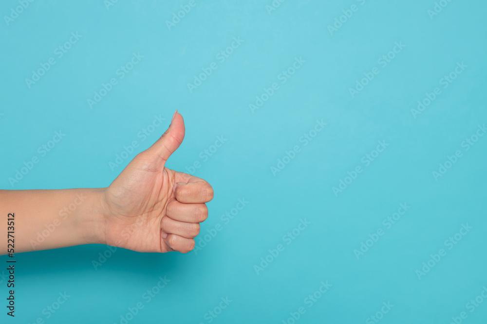 Woman showing thumb up on light blue background, closeup. Space for text Woman showing thumb up on light blue background, closeup. Space for text