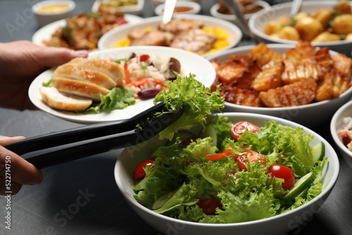 Woman taking food from buffet table, closeup