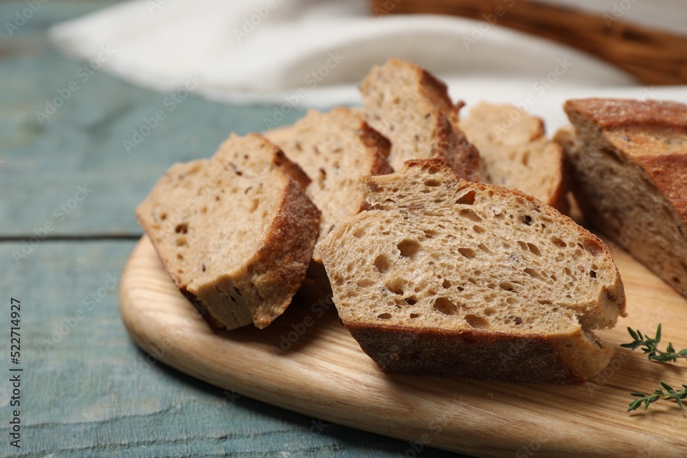 Cut buckwheat baguette with thyme on light blue wooden table, closeup Cut buckwheat baguette with thyme on light blue wooden table, closeup