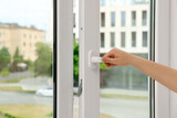 Woman opening white plastic window at home, closeup