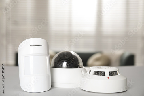 CCTV camera, smoke and movement detectors on white table indoors. Home security system