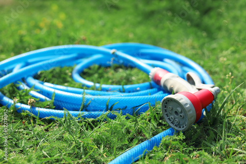 Watering hose with sprinkler on green grass outdoors, closeup photo