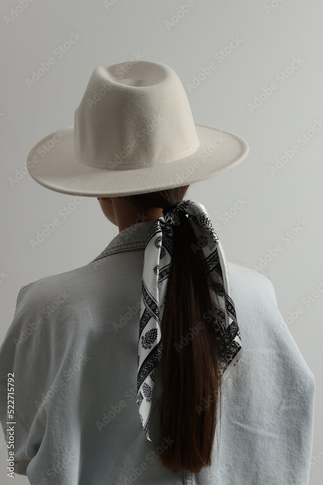 Young woman with hat and stylish bandana on light background, back view Young woman with hat and stylish bandana on light background, back view