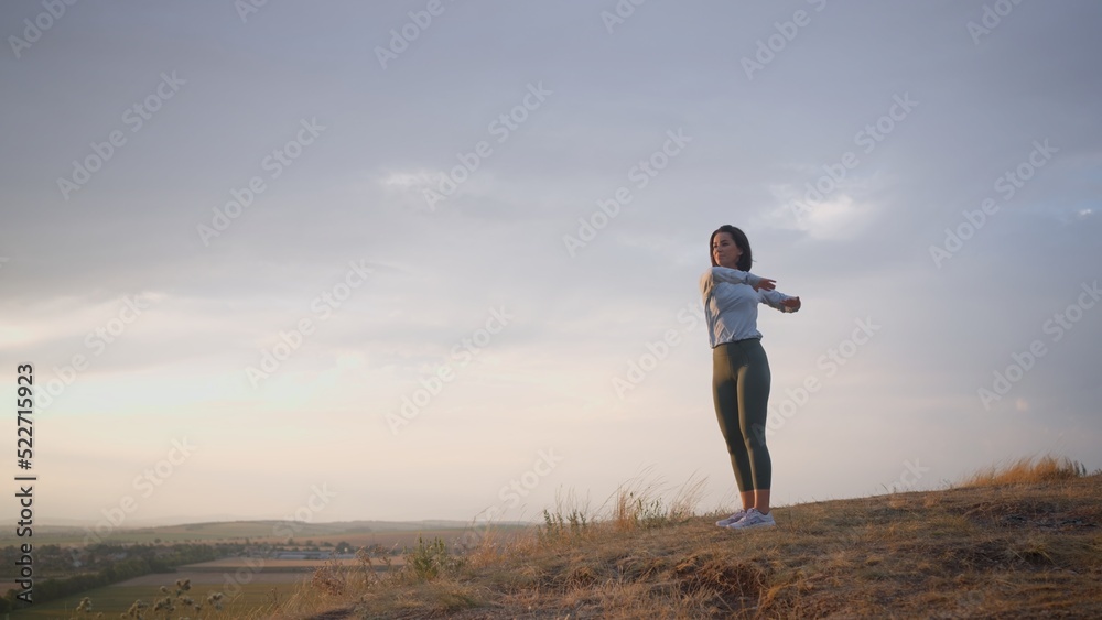 Female trail runner doing a warm-up for her hands on a high mountain Female trail runner doing a warm-up for her hands on a high mountain