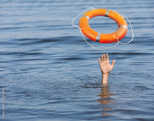 Drowning man with raised hand getting lifebelt in sea, closeup