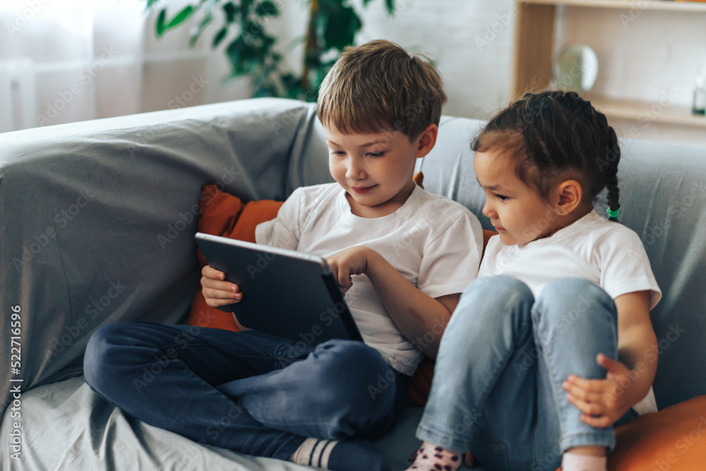 Boy and girl sitting on the couch watching video on the tablet. Boy and girl sitting on the couch watching video on the tablet.