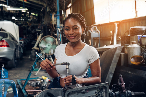 Portrait of woman auto mechanic working at car repair shop with looking at camera.