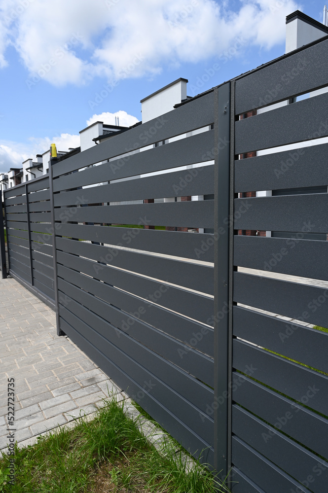Modern gray metal fence for fencing the yard area. Horizontal metal