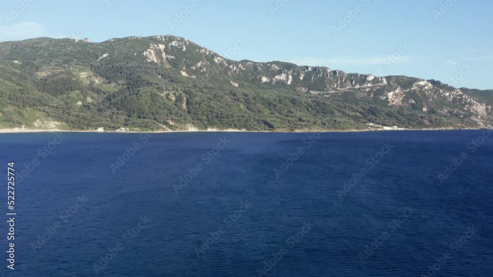 Aerial shot flying back in a Mediterranean coastline. A mountain covered in green forest meets the sea. A small sailing boat and a seagull. Aerial shot flying back in a Mediterranean coastline. A mountain covered in green forest meets the sea. A small sailing boat and a seagull.