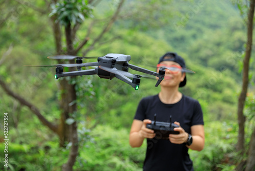 People remote control a flying drone in summer forest