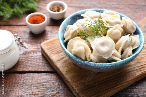 Delicious dumplings with dill on wooden table, closeup
