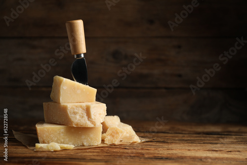 Delicious parmesan cheese and knife on wooden table. Space for text