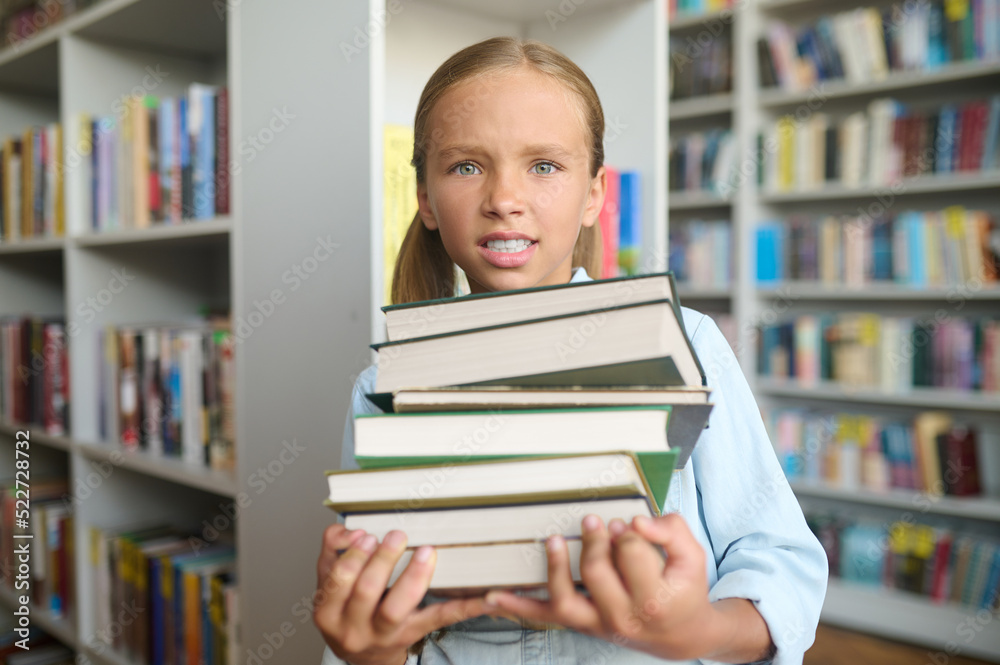 Upset schoolgirl holding textbooks in her hands
