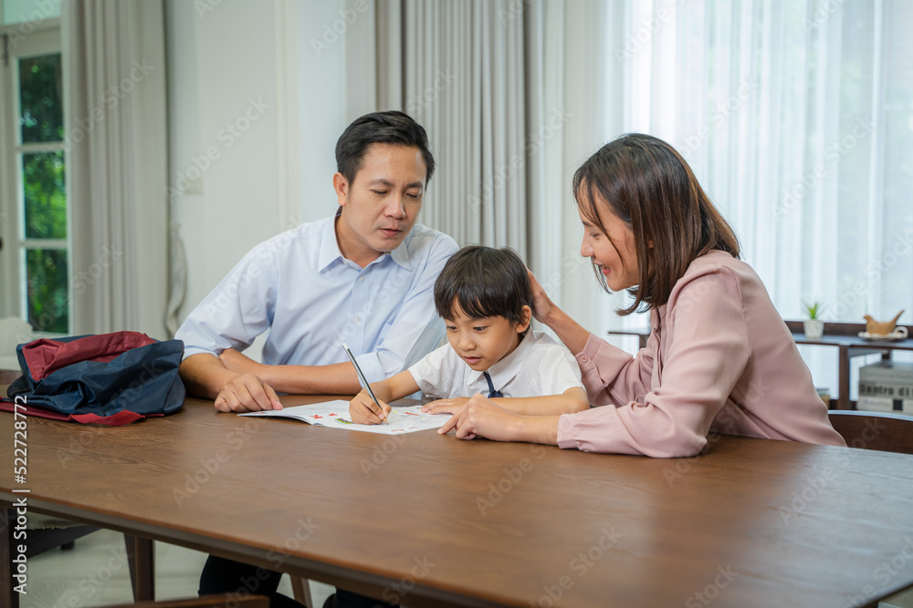Father and mother helping son with homework,Sitting at table in living room,Education,Family weekend at home. Father and mother helping son with homework,Sitting at table in living room,Education,Family weekend at home.