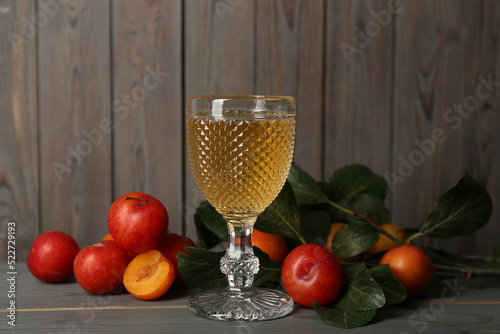 Delicious plum liquor and ripe fruits on grey wooden table. Homemade strong alcoholic beverage photo