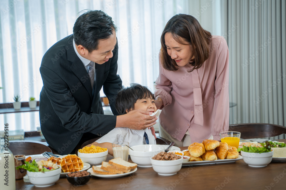 Happy family enjoying in their breakfast time in dining room before going to school.