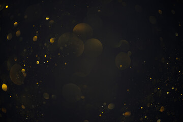 Golden bokeh lights sparkles of glitter dust particles dark abstract overlay background