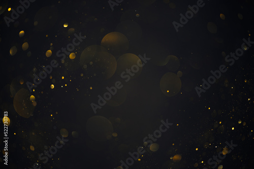 Golden bokeh lights sparkles of glitter dust particles dark abstract overlay background