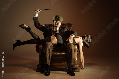 Creative portrait of man and woman in 1920s style fashion outfits isolated over dark brown background. Relationship, business, love, art, fashion photo
