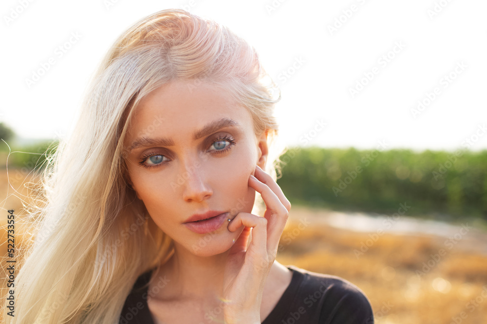 Close-up portrait of beautiful young blonde girl with blue eyes on background of sunlight. Natural outdoors photo. Close-up portrait of beautiful young blonde girl with blue eyes on background of sunlight. Natural outdoors photo.
