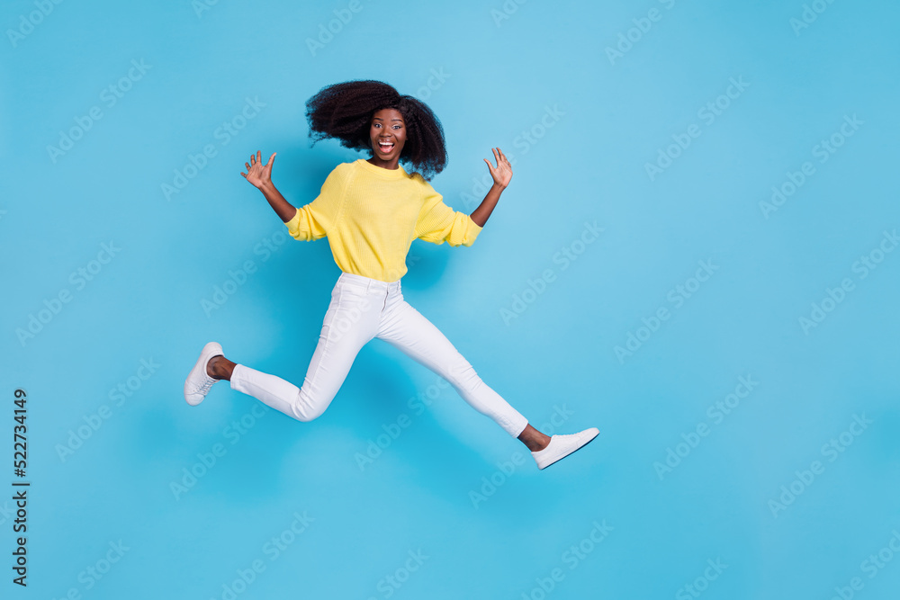 Full length photo of young happy girl hands up jump fly celebrate bought new trampoline isolated on blue color background Full length photo of young happy girl hands up jump fly celebrate bought new trampoline isolated on blue color background