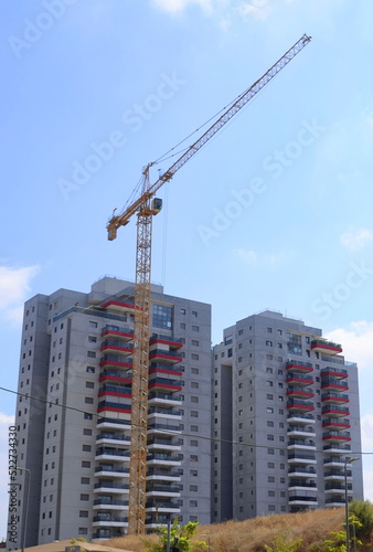 Construction of a residential building. Modern architecture. Construction crane and palm tree in the foreground. ISRAEL Rishon LeZion August 2022