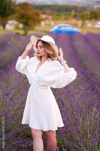 Young woman in a white dress and straw hat running in a lavender field 