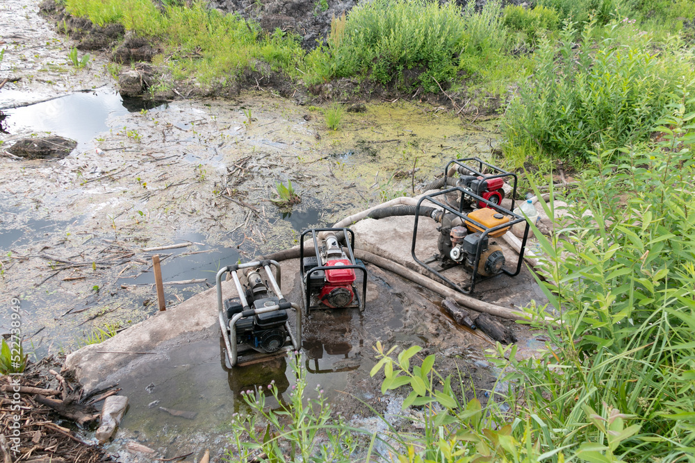 Water pumps pump water from the pond. Drainage of a reservoir, swamp
