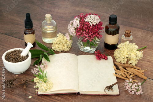 Stress reducing herbal plant medicine with valerian root, ashwagandha and elder flowers and notebook for formulas. For stress reducing natural flower remedies. On rustic wood. photo