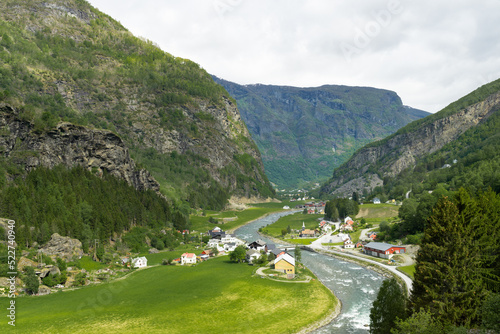 Small village with Scandinavian houses and a river surrounded by high green mountains in Norway.