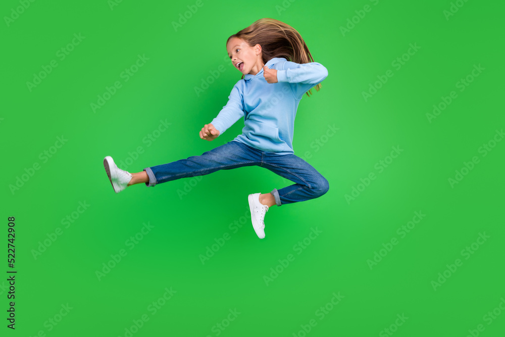 Full body photo of energetic small girl jump practicing martial arts fan dressed trendy blue sportswear isolated on green color background