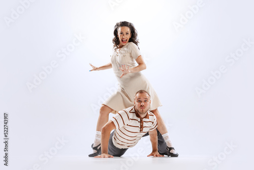 Thrilled dance couple in vintage outfits dancing lindy hop, jive isolated on white background. Art, beauty, action, 50s, 60s ,70s american fashion style